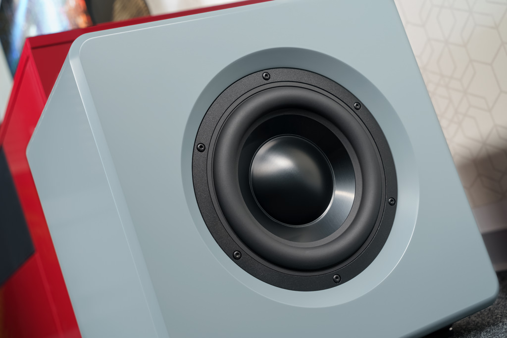 Zwei 22 Zentimeter durchmessende Premium-Tieftöner sorgen mit großer und schwerer Alu-Membran, starkem Antriebssystem und dicker Sicke für einen kraftvollen, tiefreichenden Bass. Der Spielpartner des hier sichtbaren Woofers sitzt auf der gegenüberliegenden Seite des Sub. Diese Rücken-an-Rücken-Positionierung sorgt dafür, dass die Vibrationen erzeugenden Impulse der Woofer sich kompensieren.