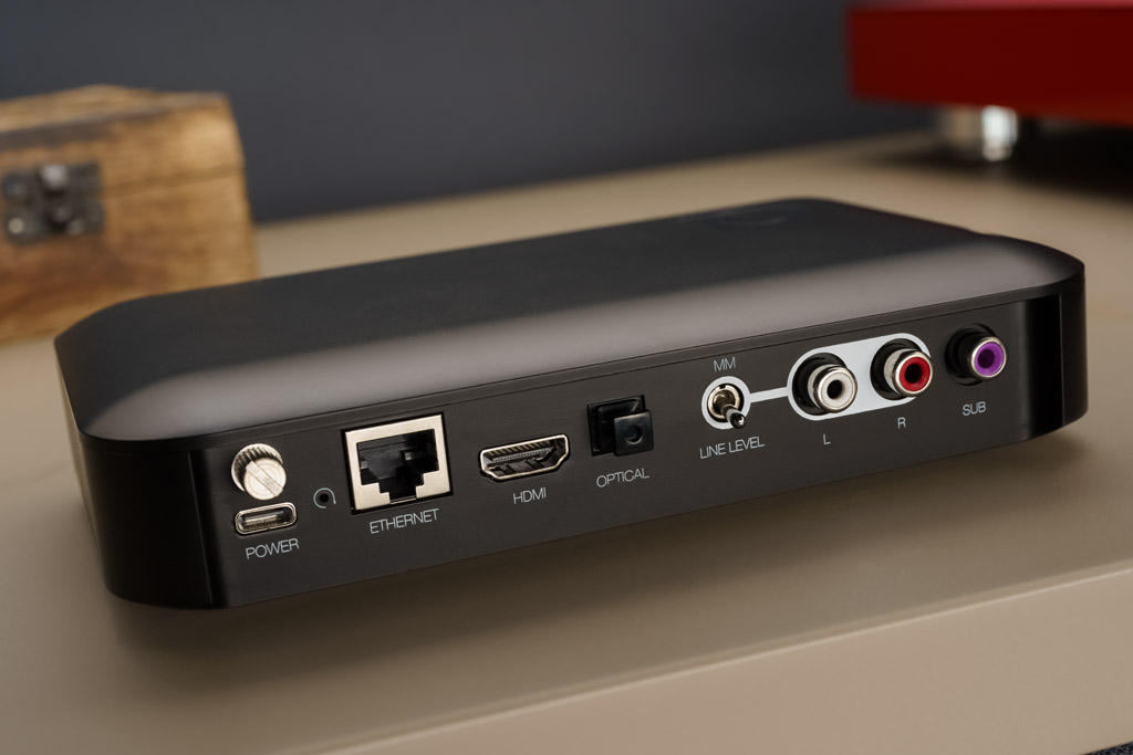 Über seine zahlreichen Wireless-Streaming-Möglichkeiten hinaus bietet das Q Active 200 auch physischen Schnittstellen: Analog ist am Hub entweder eine Line-Quelle oder ein Moving Magnet-Plattenspieler anschließbar. Digital bietet das System eine optischen Eingang, einen HDMI ARC-Input und einen LAN-Port. Über den Sub Out lässt sich für einen noch kräftigeren, tiefer reichenden Bass ein Subwoofer anschließen. Die Stromversorgung geschieht über eine USB-C-Buchse, zur Speisung wird ein externes Steckernetzteil mitgeliefert.