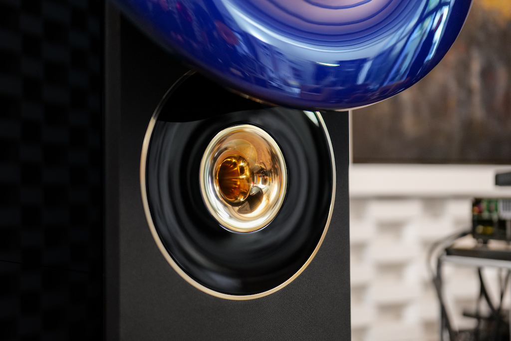 Der Ionen-Hochtöner sitzt hinter dem sphärisch geformten Horn aus purer Bronze. Im Hyperion ist dieses Horn wiederum von einer weiteren, absolut passgenau anschließenden Schallführung umgeben, die genau auf den hier eingebauten Hochtöner hin berechnet ist. Sie besteht aus schwarzem Acryl und wird an ihrem Außenrand wiederum von einem massiven Ring aus reiner Bronze eingefasst. Diese erweiterte Schallführung, die erstmals den Hyperion ziert, ist in die aufgesetzte Frontblende integriert.