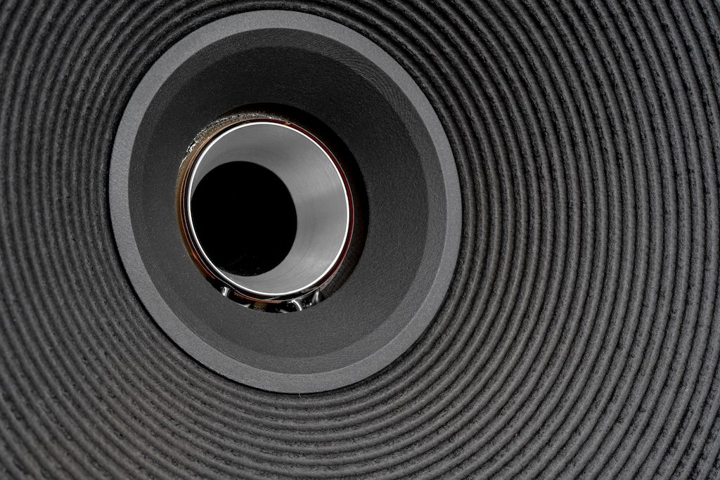 Der Tunnel, durch den der Tweeter-Schall geleitet wird, mündet vorderseitig in eine zweiteilige Schallführung. Direkt angesetzt ist ein silbermetallener Hornansatz, ihn umgibt eine schwarze Schallführung, die auf die Konusmembran des Mitteltieftöners aufgeklebt ist. Dieses Präzisionsteil aus hochsteifem, aber superleichtem Polyamid fertigt Mach One classics im 3D-Druck-Verfahren.