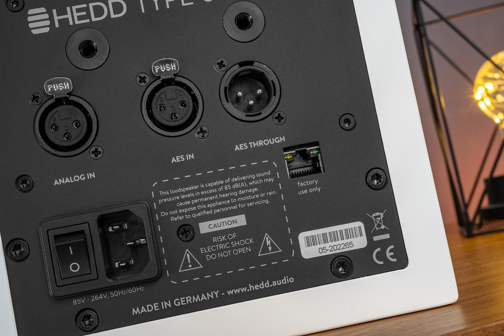 Als Studiomonitor bietet der Type 05 MK2 Profi-Schnittstellen: Analogseitig ist er mit einem symmetrischen XLR-Eingang ausgestattet, digital mit einem AES3/EBU-Input. Zum Anschluss weiterer Monitore für den Stereo- oder Mehrkanal-Betrieb dient die „Through“-Buchse: Hier liegt das durchgeschleifte Digitalsignal an. Diese beiden Schnittstellen sind ebenfalls in XLR realisiert. Hat man einen Zuspieler mit Cinch-Ausgängen beziehungsweise S/PDIF-Schnittstellen, gelingt der Anschluss mit entsprechenden Adaptern. Oberhalb der Anschlüsse sind M6-Gewindebuchsen für die Wandmontage eingelassen.