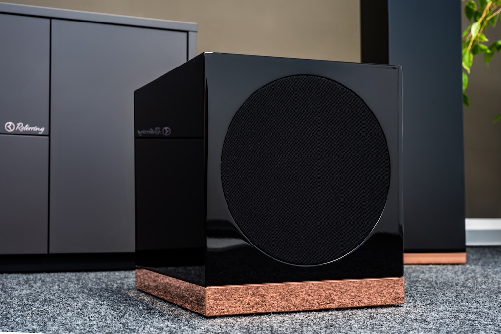 Der neue, optional erhältliche Subwoofer setzt optisch den Luxus-Look fort – und erweitert akustisch die Tiefton-Fähigkeit des M1: So spielt das System bis 30 Hertz hinunter. Da dieser Subwoofer ebenfalls mit einem geschlossenes Gehäuse realisiert ist, kann der Bass-Kubus auch wandnah aufgestellt werden.