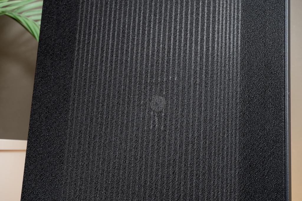 Durch den Stoff hindurch kann man die Leiterbahnen der Magnetostat-Membran sehen. Sie werden in Magnepans Manufaktur in Handarbeit auf die Folienfläche aufgeklebt. Rechts befindet sich der Hochtonbereich, in dem die Leiterbahnen enger beieinander liegen. Lins sehen wir das deutlich größere Areal für Mitten und Bässe, hier haben die Bahnen einen größeren Abstand.