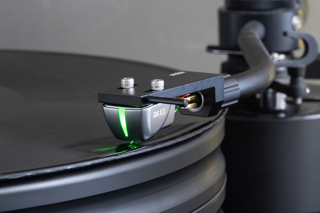 Magisches Leuchten: Der Soulnote E-2 kann auch das Signal fotoelektrischer Abtaster von DS Audio handhaben. Sie benötigen eine Speisung für den Betrieb der optischen Wandler-Einheit. Und wo die Stromversorgung schon mal da ist, kann man sie auch für eine eindrucksvolle Illumination nutzen. Sie ist zugleich ein Farbcode, mit dem man die verschiedenen Systeme von DS Audio erkennen kann. Hier ist das Modell DS E3 montiert. Das System hat uns der deutsche Vertrieb High Fidelity Studio zur Verfügung gestellt.