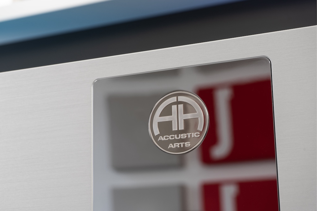 Nobles Design: Die hochglänzende und spiegelglatte Chromblende ist absolut bündig als edle Intarsie in die Front eingelassen. In dieses Inlay ist wiederum die Medaille mit dem siegelartigen Accustic-Arts-Logo eingelegt.