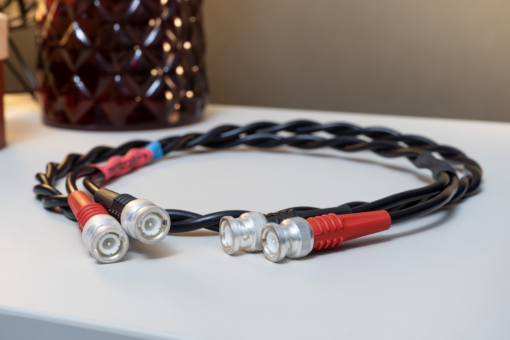 Das NF-Kabel PK2 MK 3 gehört zum Lieferumfang. Es besteht aus einem Paar einzeln abgeschirmter und verzinnter Kupfer-Innenleiter-Litzen, einer Isolation aus Polyethylen und einer Ummantelung aus PVC. Das Kabel ist beidseitig als BNC-Kabel konfektioniert. Für den Anschluss an den nachfolgenden Verstärker braucht man, wenn er keine BNC-Buchsen besitzt, Adapter. Diese gehören ebenfalls zum Lieferumfang.