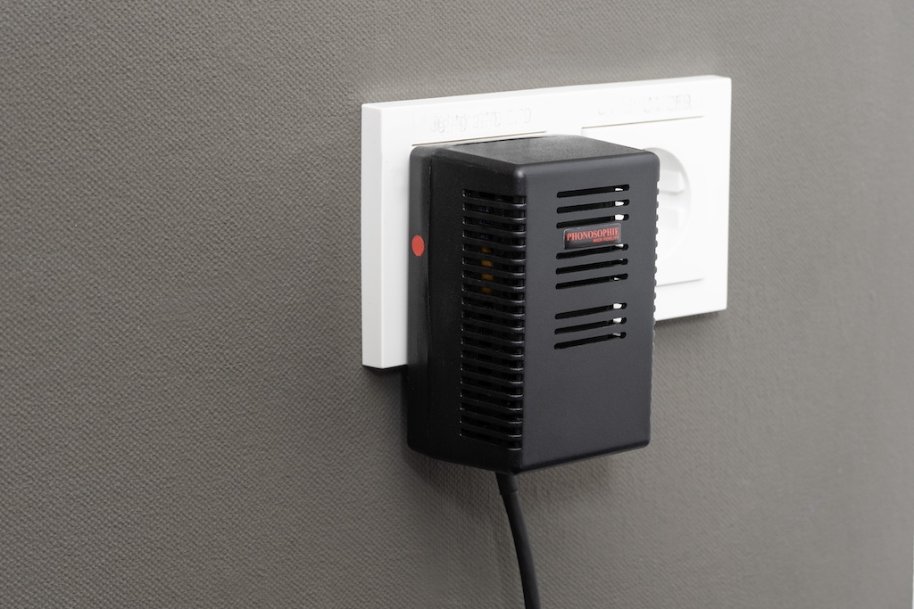 Die Stromversorgung übernimmt ein externes Steckernetzteil. Es ist leistungsstark realisiert und linear aufgebaut, also mit einem echten Trafo. So liefert es eine saubere und stabile Spannung und stört dank der Auslagerung auch nicht die empfindliche Audio-Elektronik. Der rote Punkt markiert die Phase: Durch phasenrichtigen Anschluss aller Audio-Komponenten minimiert man Potenzialunterschiede und daraus resultierende vagabundierende Ströme, die etwa zu Trafo-Brummen führen.