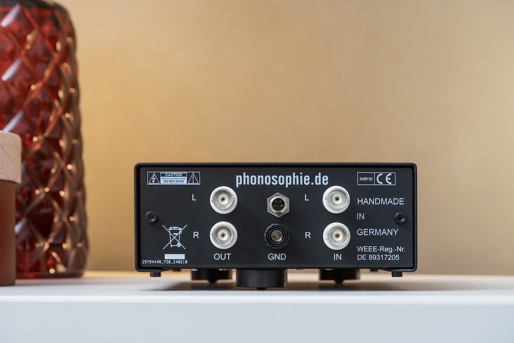 Die Rückseite bietet ein- wie ausgangsseitig ein Paar BNC-Buchsen für den Anschluss der Signal-Kabel. Phonosophie attestiert dieser Norm eine klangliche Überlegenheit. Zur Erdung dient die Ground-Klemme. An die vierpolige Buchse wird das externe Netzteil angeschlossen.
