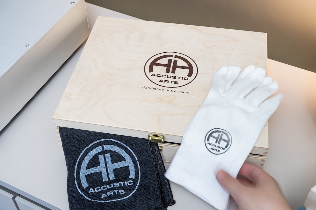Das umfangreiche Zubehör liefert Accustic Arts in einer aparten Holz-Schatulle. In ihr liegen neben der Fernbedienung samt Batterien, einem Netzkabel, einer Ersatzsicherung und der Bedienungsanleitung samt Qualitätsprüfungszertifikat auch ein Reinigungstuch und Handschuhe.